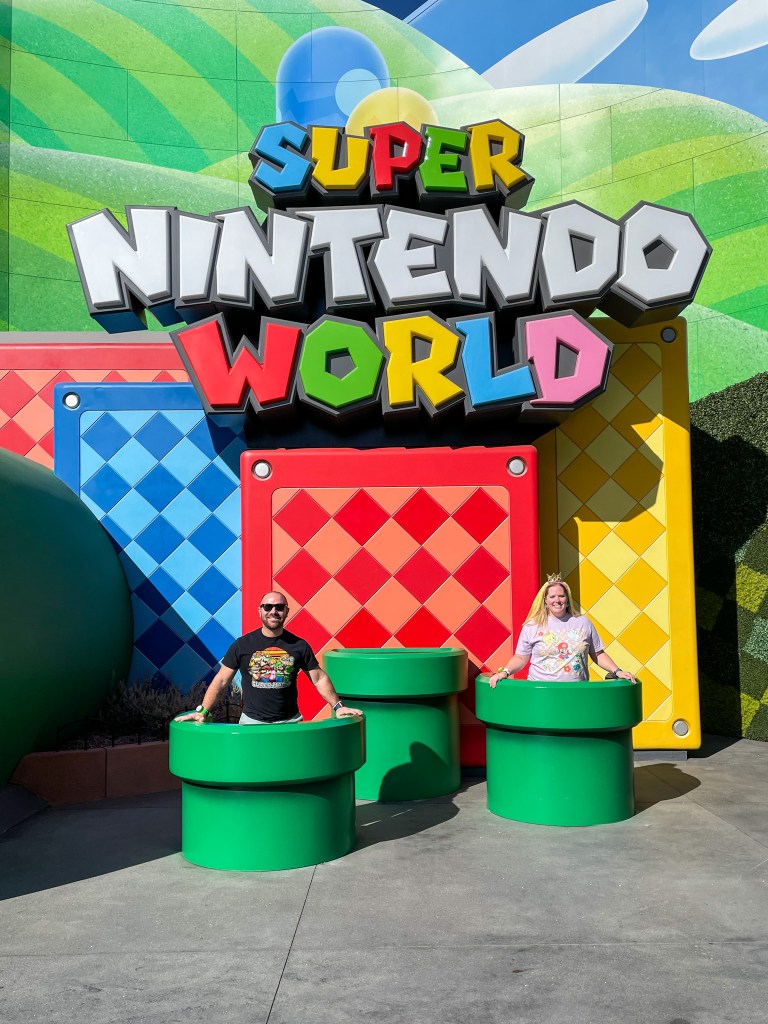 Emily and Mike in warp pipes in front of Super Nintendo World sign | Traveling Twogether